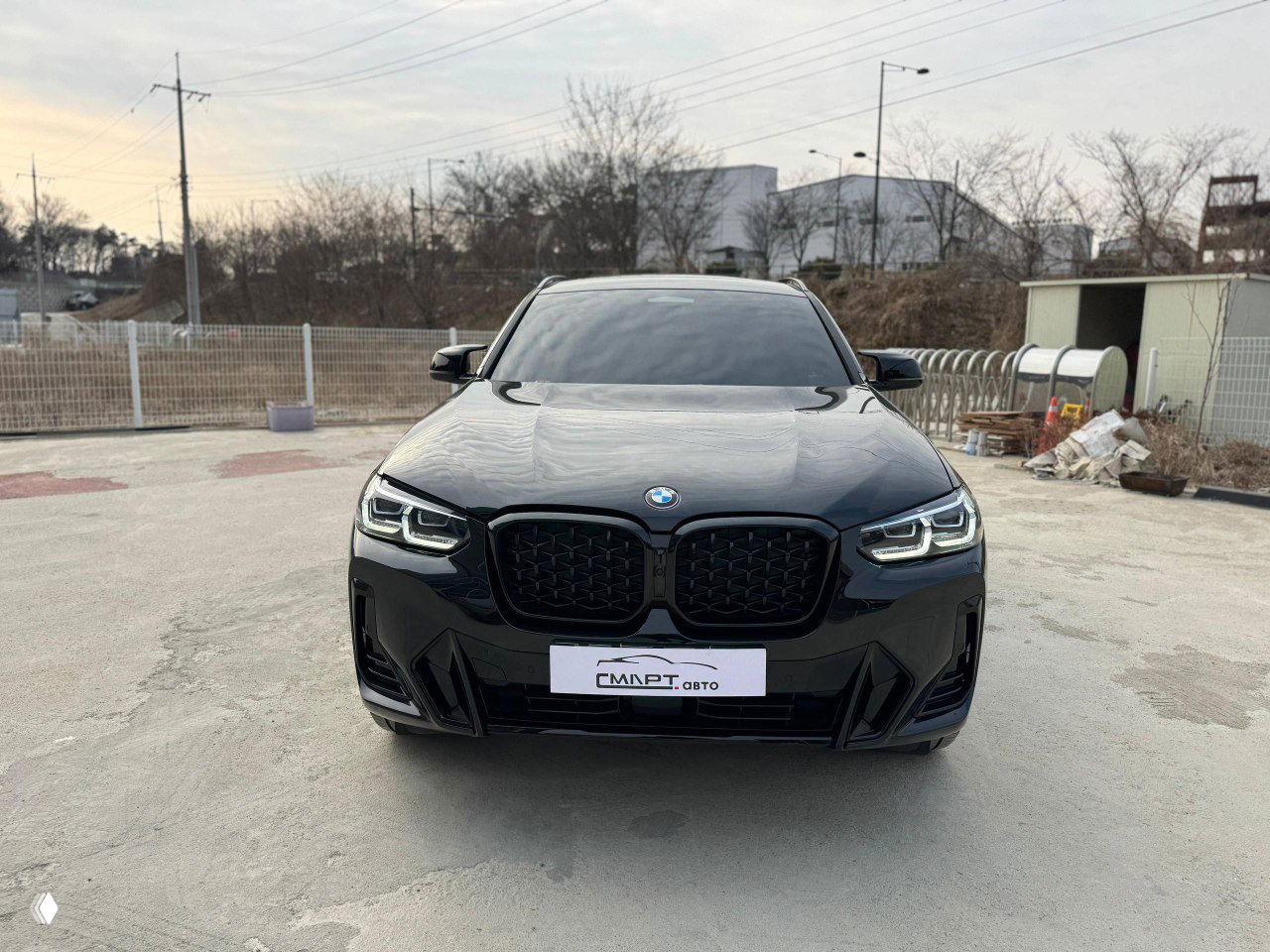 Фронтальный вид чёрного BMW X4 2025 года: крупная решётка радиатора, светодиодные фары и эмблема BMW на капоте.
