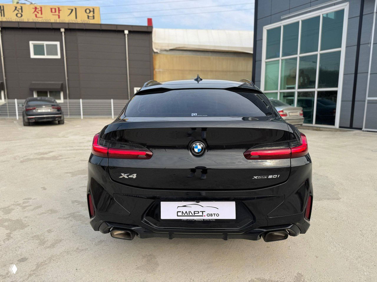 Нижний задний ракурс чёрного BMW X4, крупный план кормы и шильдик X4, подчёркнутые линии бампера и диффузор.