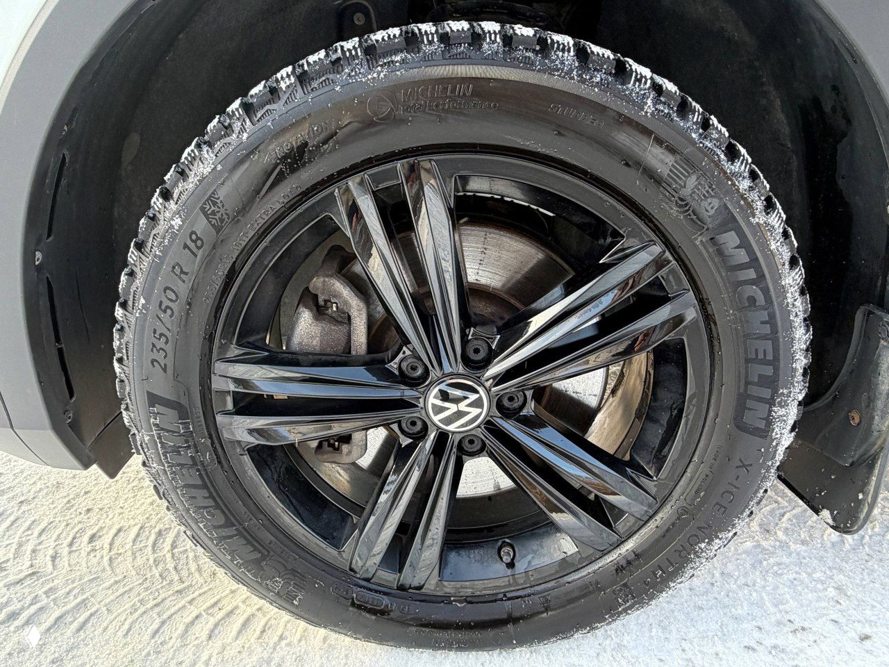 Крупный план чёрного легкосплавного диска Volkswagen с маркировкой Michelin на зимней шине и видимым тормозным диском.
