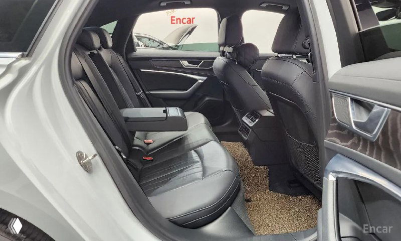 Задний ряд сидений Audi A6 с чёрной кожей, складным подлокотником и видимыми дефлекторами обдува и ковриками в салоне.