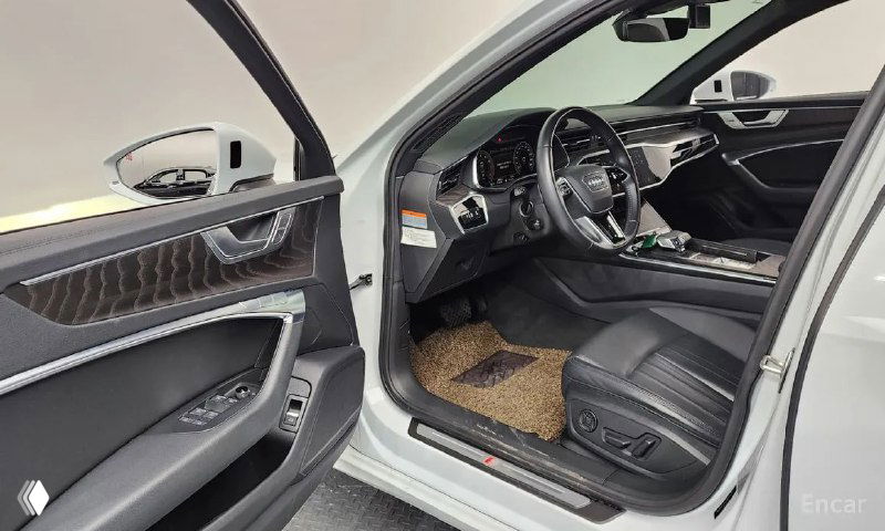 Открытая водительская дверь Audi A6: вид на дверную панель, регулировки сиденья, часть рулевой колонки и передней панели салона.