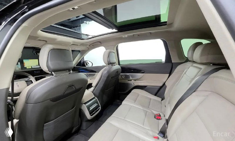 Задний ряд сидений Lincoln Nautilus 2023: светлая кожа, просторный салон, вид на подголовники и часть панорамной крыши сверху.