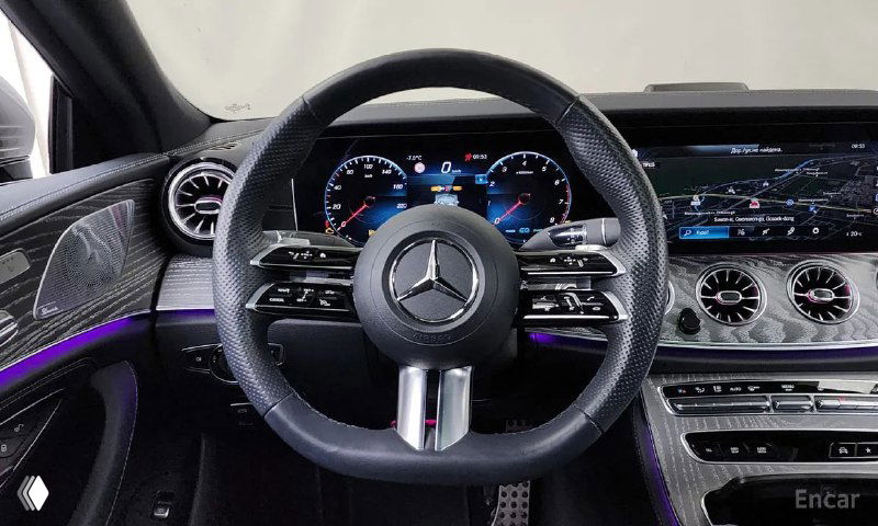 Вид салона через руль: передняя панель Mercedes‑Benz CLS450, мультируль, цифровая приборная панель и центральный дисплей с подсветкой.