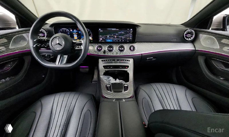 Панорамный вид интерьера Mercedes‑Benz CLS450: центральная консоль, сиденья и декоративная подсветка, видна конфигурация передних мест.