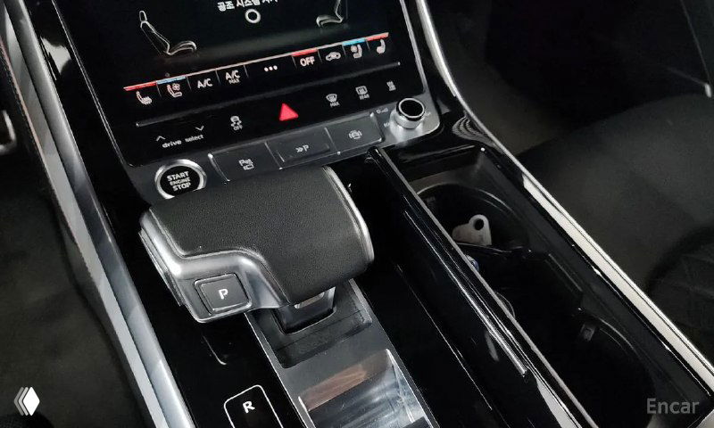 Деталь консоли Audi Q8: селектор коробки передач, сенсорные панели управления климатом и элементы отделки, поверхности без видимых повреждений.