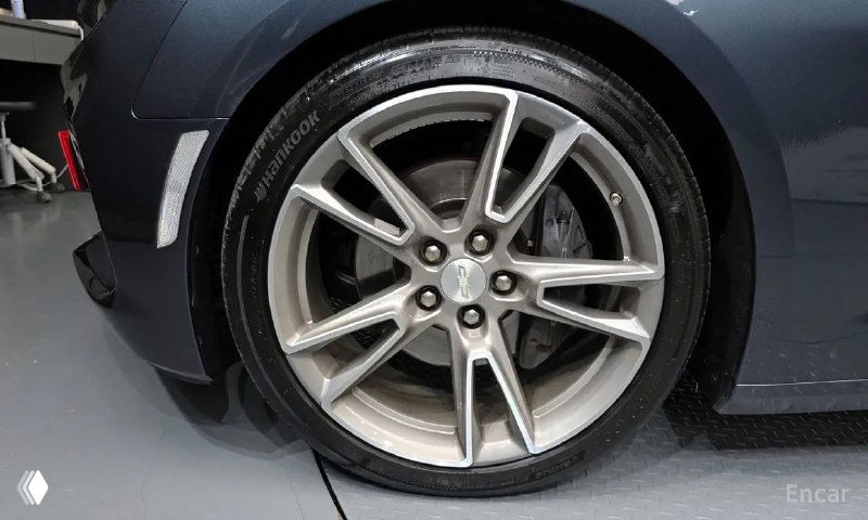 Крупный план переднего колеса и диска Chevrolet Camaro SS 2021, на диске видно следы эксплуатации и дизайн легкосплавного диска.
