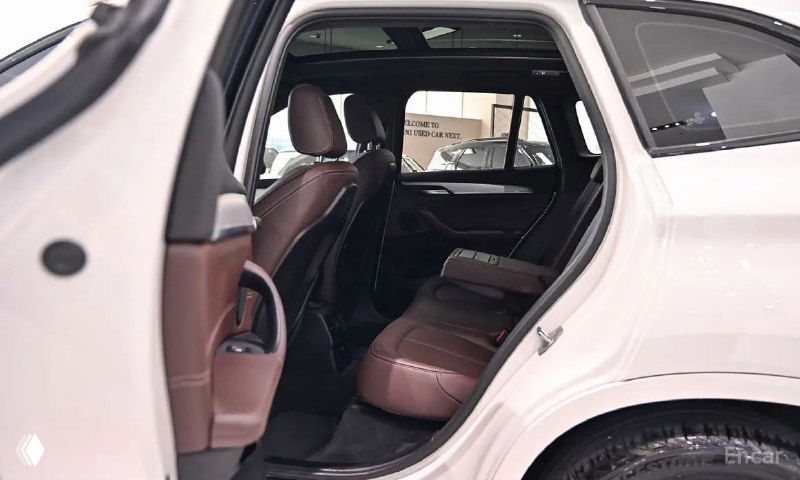 Задняя дверь и сиденья BMW X1: вид на пространство для пассажиров, коричневая кожаная обивка и чистый салон без следов износа.