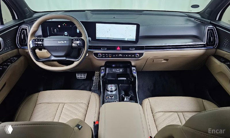 Салон Kia Sorento: передние пассажирские и водительское сиденья бежевого цвета, центральная консоль и большой сенсорный экран на торпеде.