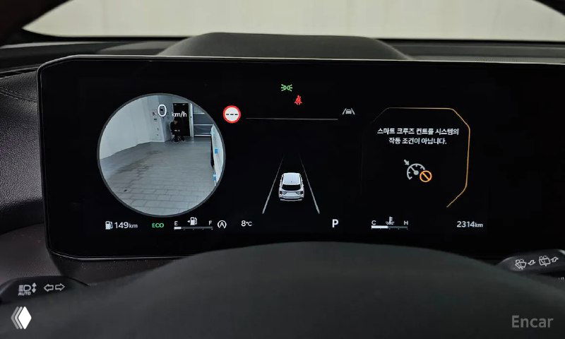 Штатная приборная панель Kia Sorento с левой камерой кругового обзора на экране и отображением систем помощи водителю в рабочем режиме.