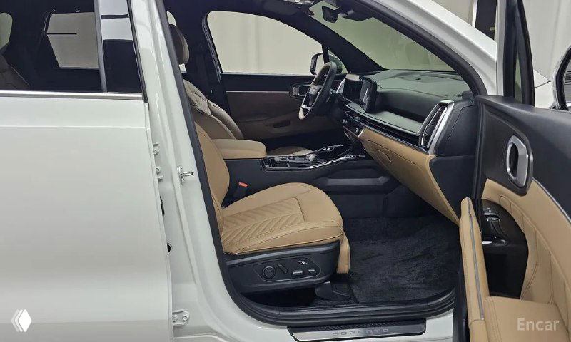 Вид на передние сиденья и центральный тоннель Kia Sorento с рабочими элементами управления и посадочной зоной, подчёркнутой светлой обивкой.