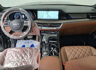 Интерьер передней части Kia Mohave: коричневые стёганые сиденья, панель приборов и широкий мультимедийный экран — салон в антуражной студии.