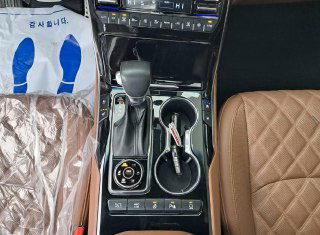 Центральная консоль Kia Mohave с селектором коробки, органами управления, подстаканниками и вставками чёрного глянца — салонный ракурс крупным планом.