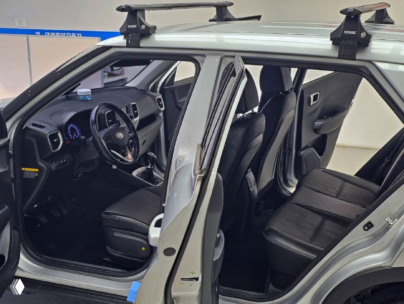 Вид салона Hyundai Venue крупным планом: передние сиденья, рулевая колонка и центральная часть передней панели в выставочном освещении.