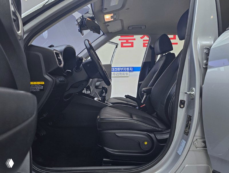 Крупный план водительского места Hyundai Venue: сиденье водителя, руль, приборная панель и часть передней консоли — подчёркнута механическая коробка передач.