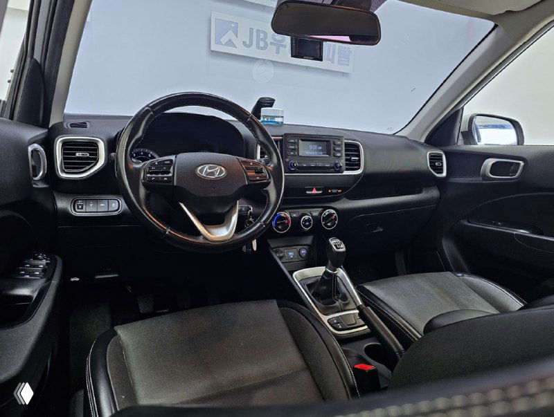 Передняя панель и руль Hyundai Venue: мультимедийный экран, блок управления климатом и центральная консоль с видимым селектором механической коробки передач.