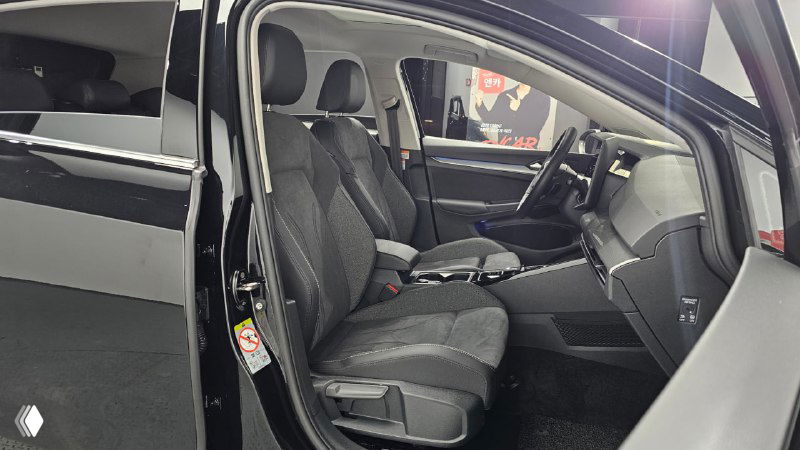 Боковой вид на переднее пассажирское сиденье и центральный тоннель с подлокотником в салоне Volkswagen Golf, серые тканевые вставки на сидениях.