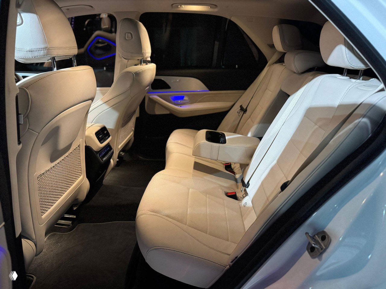 Задние пассажирские сиденья Mercedes GLE в бежевой кожаной обивке, камера показывает пространство для ног и подлокотник.