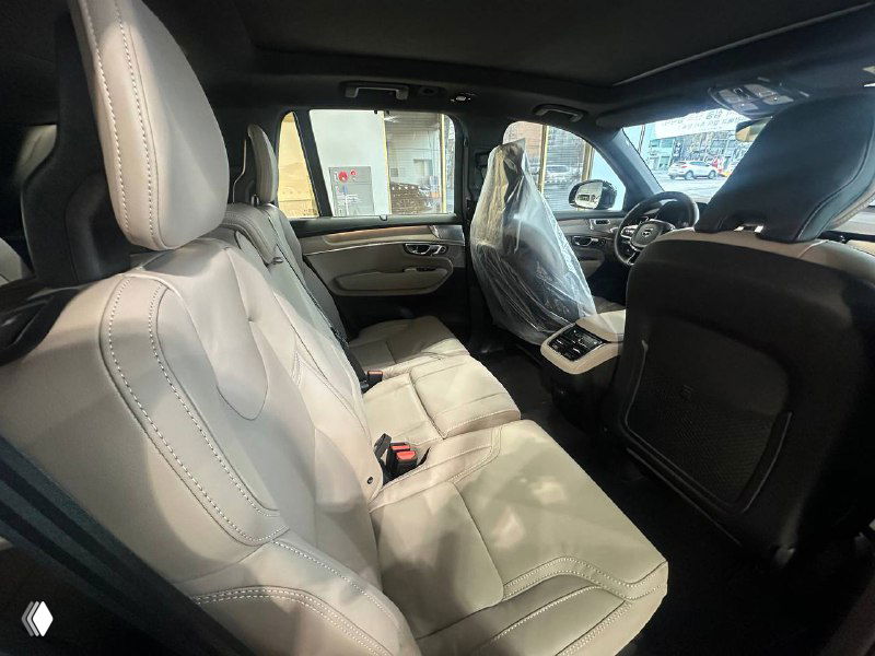 Салон Volvo XC90 T8, задние сиденья в светлой отделке, защитные плёнки на передних креслах и просторный интерьер дилерского экземпляра.