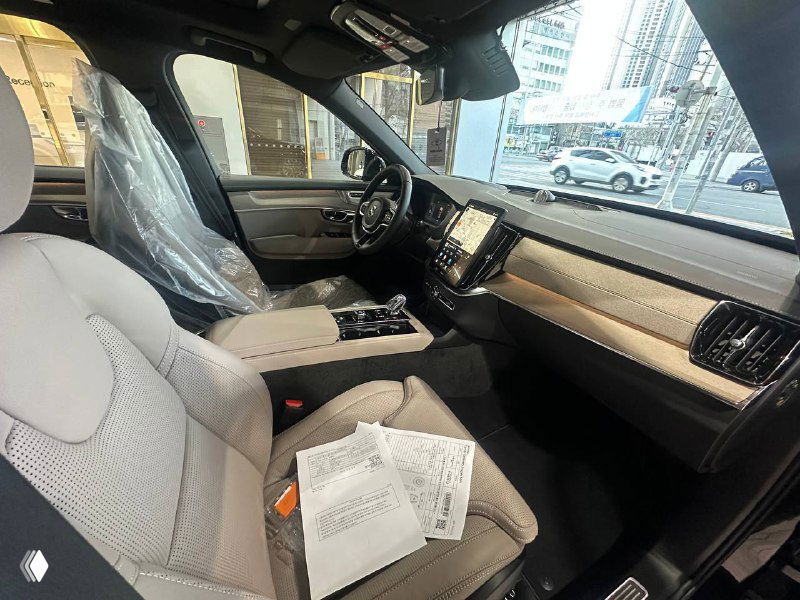 Сиденье переднего пассажира Volvo XC90 T8 с документами на сиденье, центральная консоль и детали интерьера на фото из дилерского зала.