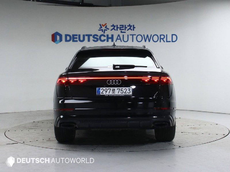 Задняя часть чёрного Audi Q8 55 TFSI Quattro на поворотном подиуме, видна светотехника и номер; интерьерная подсветка в отражениях