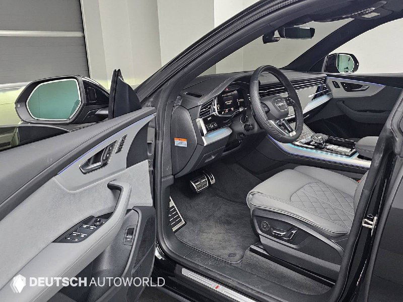 Открытая передняя дверь Audi Q8, вид на водительское место, кресло в кожаной отделке, порог и органы управления на двери