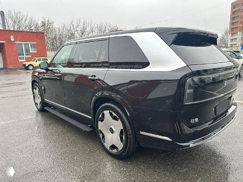 Трёхчетвертной боковой вид Zeekr 9X на парковке: чёрный кузов, крупные колёсные диски и контрастные серебристые элементы крыши на фоне домов.