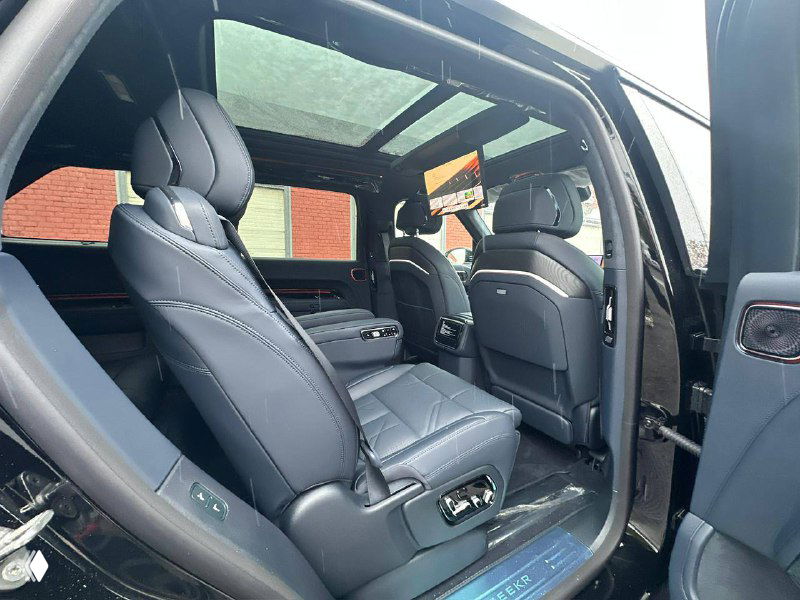 Вид на задние поворотные кресла Zeekr 9X: кожаная обивка, регулировки и пространство между креслами, салон открыт и освещён.