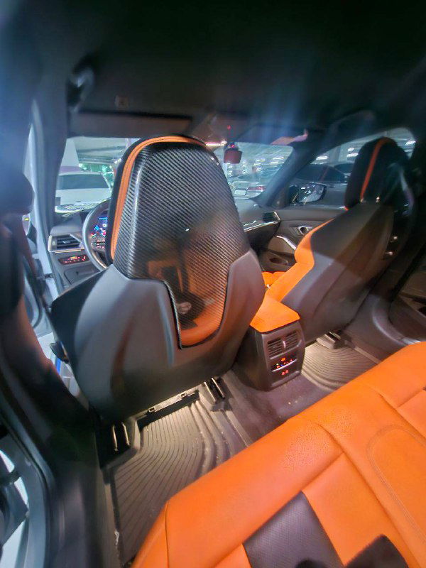 Задний ряд BMW M3 Touring с оранжевой обивкой, видны подголовники, посадочные места и пространство для пассажиров.