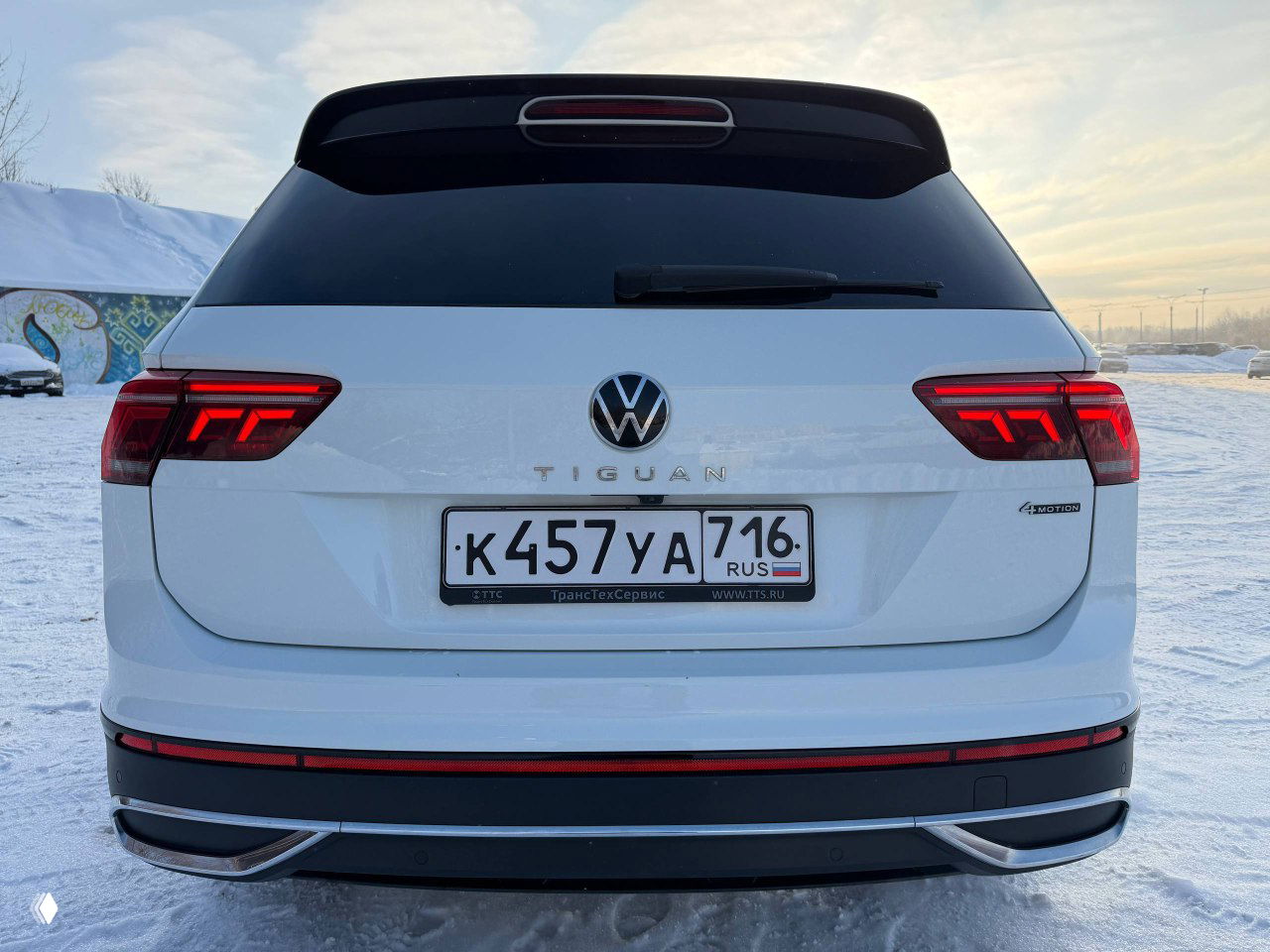 Крупный план задней части белого Volkswagen Tiguan Urban Sport 2022 с хорошо читаемым номерным знаком и оптикой, показаны линии крышки багажника и спойлера.