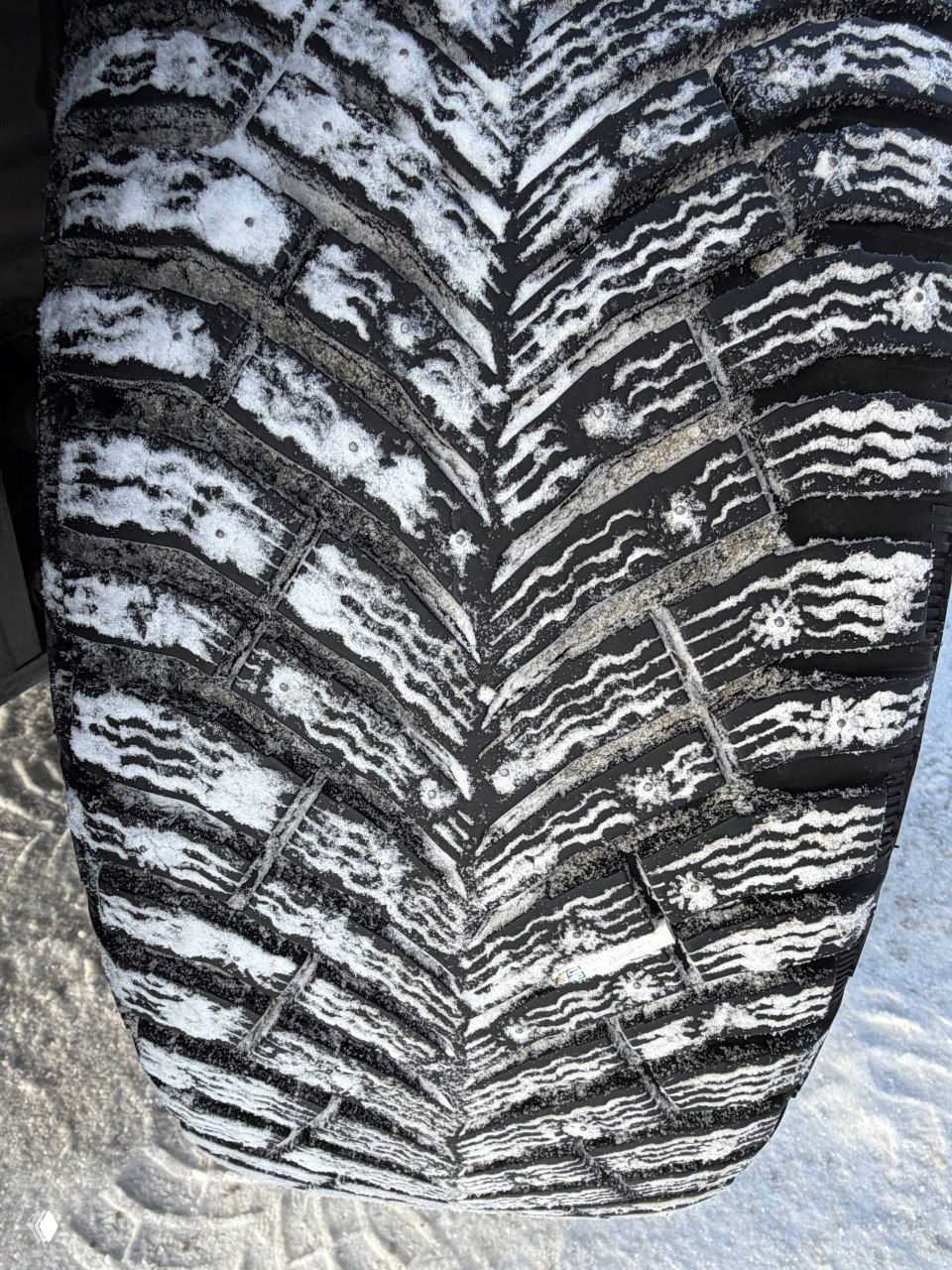 Крупный снимок протектора зимней шины Michelin от Volkswagen Tiguan Urban Sport 2022 с заметным рисунком и следами снежной смеси в канавках протектора.