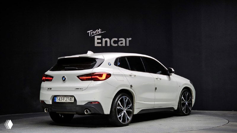 Белый BMW X2 (F39) вид сзади-угла на студийном фоне, заметны задние фонари и часть номерного знака, фотография для объявления о продаже.