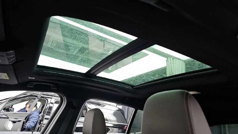 Панорамная крыша и люк BMW X2, вид из салона вверх, стеклянная крыша пропускает свет, демонстрация опции люка в автомобиле.