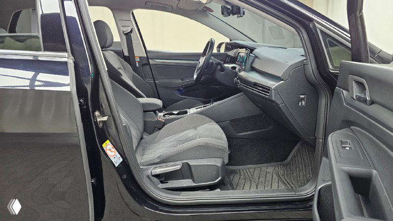 Вид на передние сиденья Volkswagen Golf 2022 со стороны пассажира — центральная консоль, передняя панель и общее состояние интерьера, чёрная обивка.