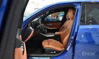 Переднее пассажирское кресло и открытая дверца BMW G20 в автосалоне, коричневый кожаный салон и отделка, кадр крупным планом на сиденье.