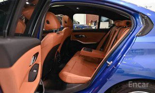 Задний ряд сидений BMW 3 серии (G20) в коричневой коже, вид через открытый задний боковой проём, простор и отделка салона наглядно показаны.