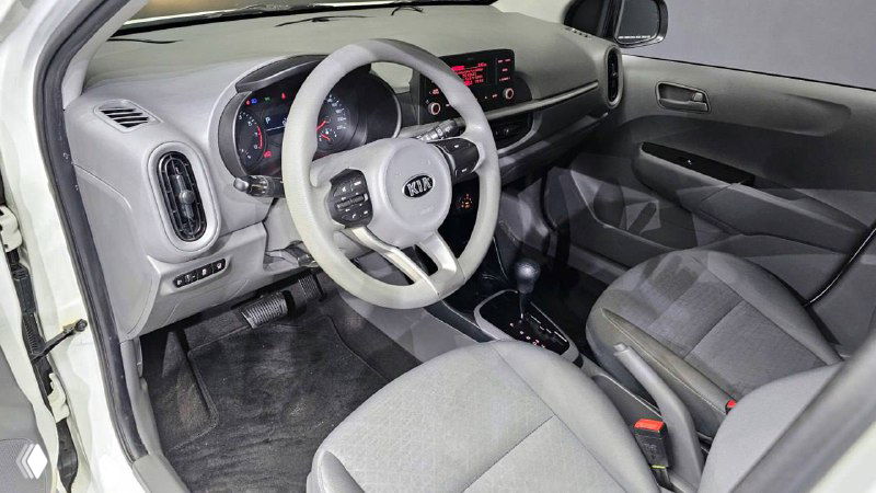 Салон Kia Morning Urban: передняя панель, руль, сиденья и приборная панель, серые тканевые чехлы, общий аккуратный интерьер без видимых повреждений.