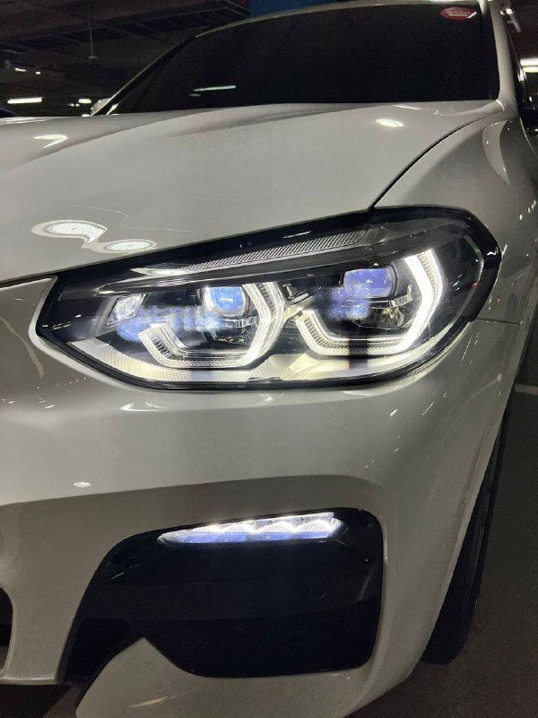 Фара и передняя часть бампера BMW X3 M Sport крупным планом, видно светодиодную оптику и элементы переднего сплиттера в белом кузове.
