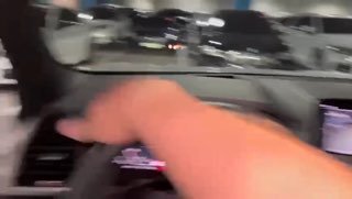 Кадр из видео: рука водителя тянется к рулю и центральной консоли, видна приборная панель и элементы салона BMW X3 в движении.