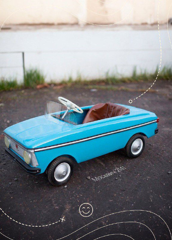 Голубая педальная машина СССР на пустой площадке, крупный план корпуса и руля, видны ретро‑детали и лаковая краска в хорошем состоянии.