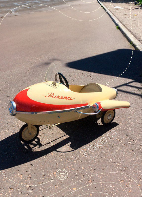 Педальная игрушечная ракета‑машина кремово‑красного цвета на асфальте, обтекаемая форма в стиле ретро и белые колёса, фото в дневном свете.