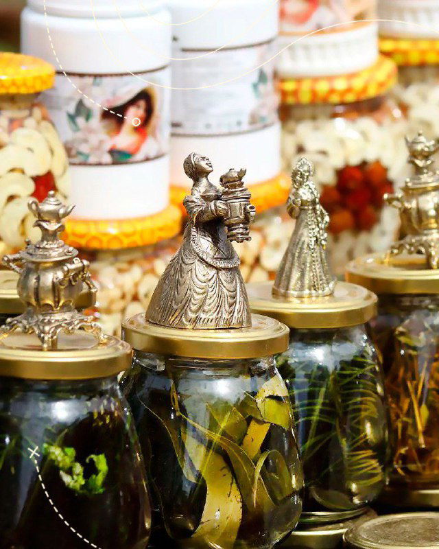 Ряд стеклянных банок с соленьями и небольшими сувенирами на прилавке ярмарки, атмосфера местного рынка и ремесленных лавок фестиваля Крапивы.