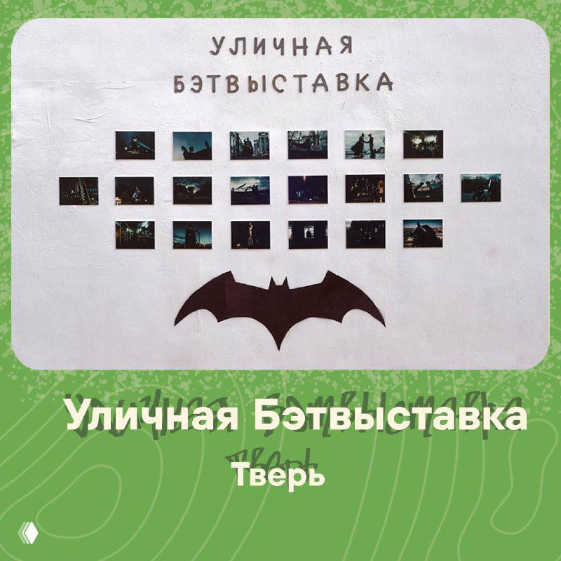 Панель уличной фотовыставки «Уличная Бэтвыставка» в Твери: ряды фотообъектов и символ бэтмена на белом фоне на уличной инсталляции.