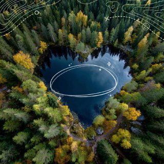 Вид с дрона на тёмное сердцеобразное озеро среди осеннего леса с графической белой разметкой вокруг воды, подчёркивающей форму.