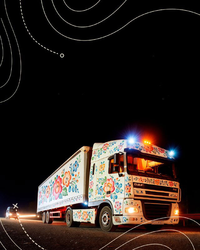 Ночной кадр грузовика, полностью украшенного традиционной росписью Семикаракорска, с включенными фарами и узорами по борту и кабине.