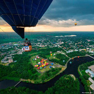 Кабина воздушного шара над городом Великие Луки: панорама реки, парков и площадки фестиваля — вид полёта над местом события.
