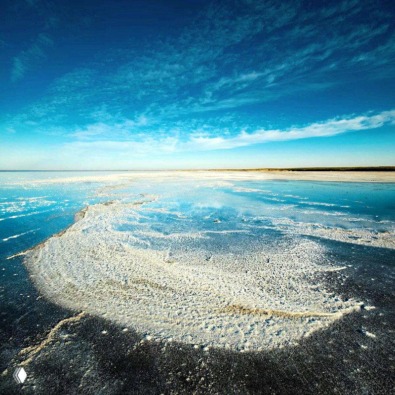 Соляные кристаллы и белые отложения на поверхности минерализованного озера Эльтон, ощущение солончаков и широких горизонтов.