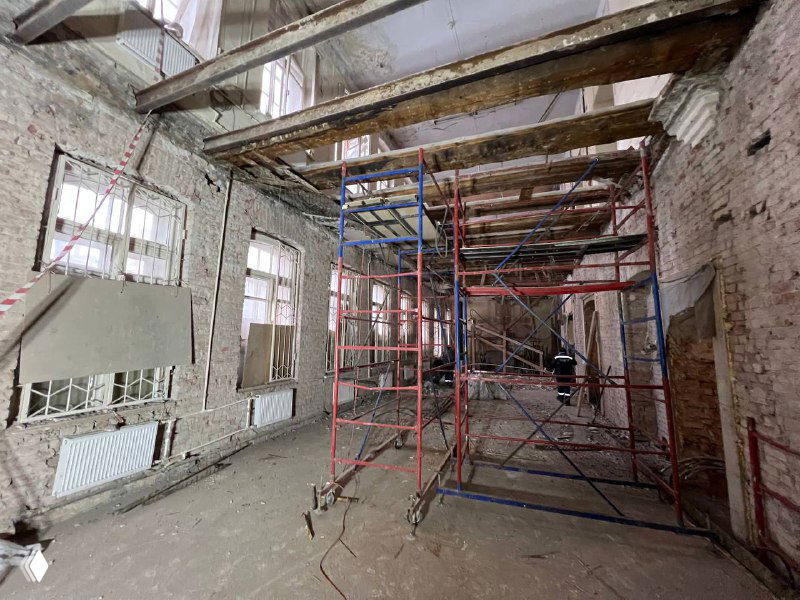 Широкий ракурс рабочего пространства с лесами и опорами, видно состояние стен и окна — этап демонтажа перед монтажом нового перекрытия.