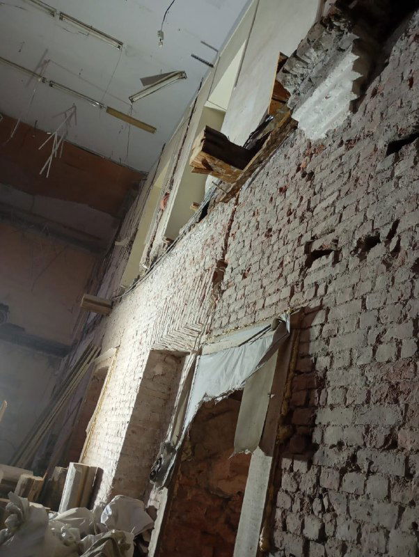 Крупный план кирпичной стены с видимыми очагами разрушения и отвалившейся штукатуркой в зоне демонтажа перекрытия.