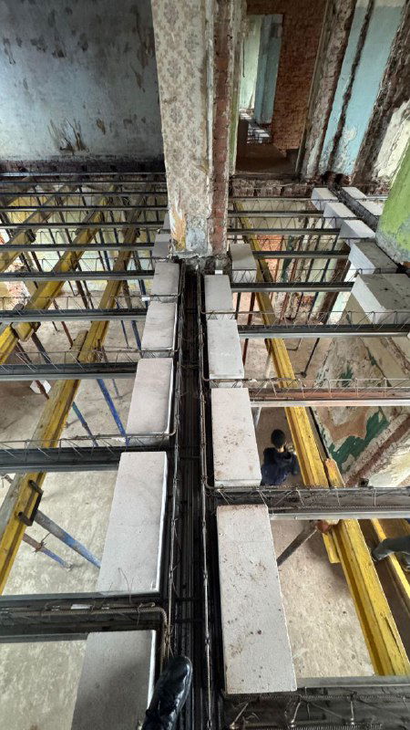 Внутренний вид демонтажных работ и установки облегчённых сборно‑монолитных перекрытий: металлические балки, блоки и временные опоры в помещении общежития.