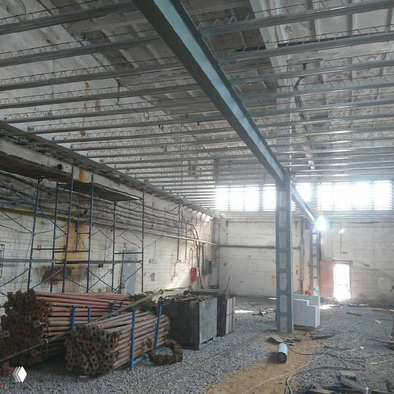 Промежуточная стадия реконструкции: складской уголок с металлическими балками и частично демонтированными конструкциями, подготовка пространства под новые этажи.